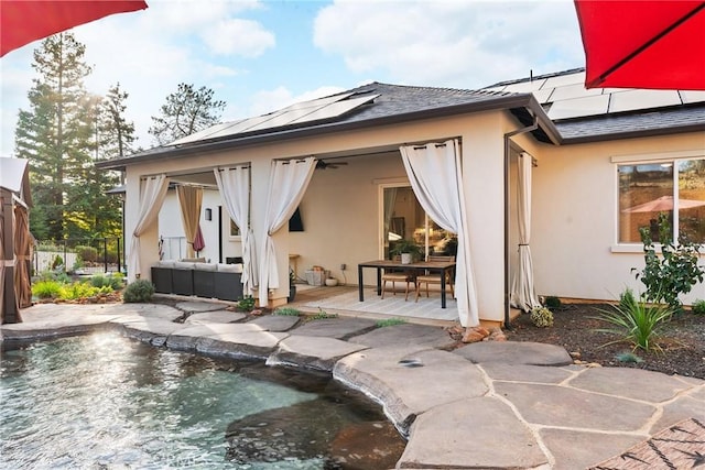 back of house featuring solar panels, ceiling fan, a patio area, and an outdoor living space