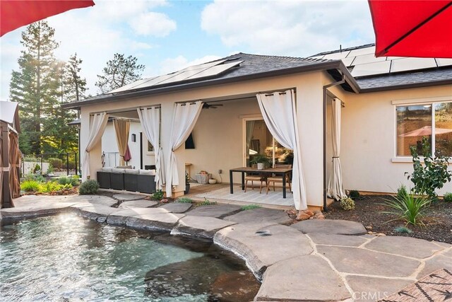 5772 Acorn Ridge Dr, Paradise, CA 95969 - back of property featuring stucco siding, solar panels, outdoor lounge area, and ceiling fan