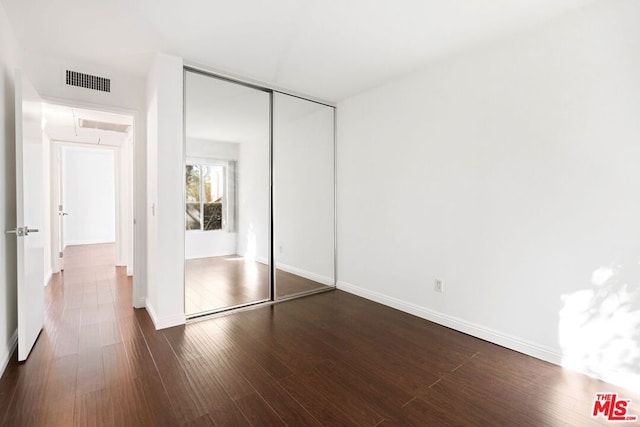 unfurnished bedroom featuring dark hardwood / wood-style floors and a closet