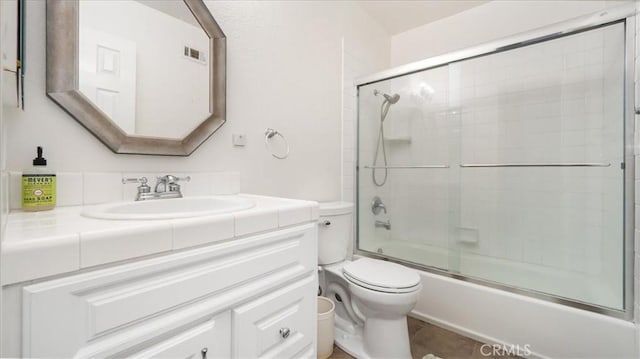 full bathroom with vanity, bath / shower combo with glass door, and toilet