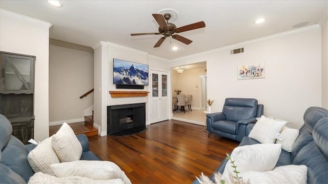 living room with a fireplace, dark hardwood / wood-style flooring, ceiling fan, and ornamental molding