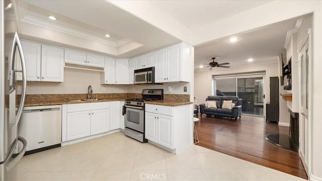 kitchen featuring appliances with stainless steel finishes, light wood-type flooring, white cabinetry, and ceiling fan