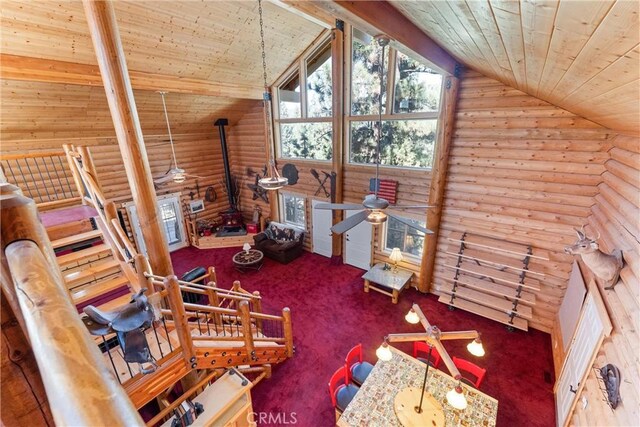 bonus room featuring wood ceiling, carpet flooring, log walls, vaulted ceiling, and a wood stove