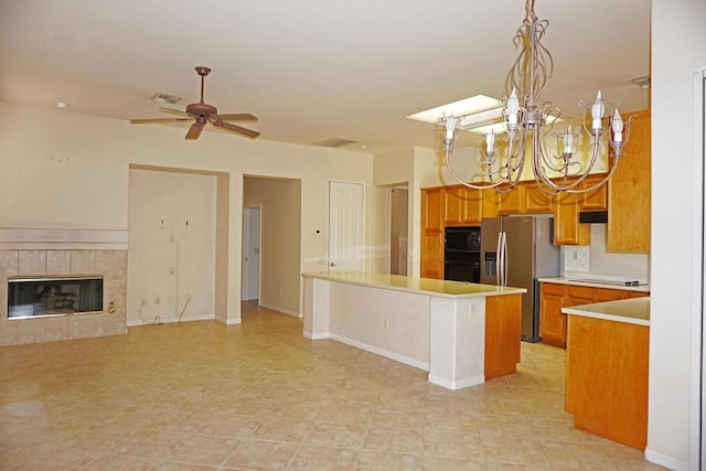 kitchen featuring a tile fireplace, pendant lighting, ceiling fan with notable chandelier, black appliances, and kitchen peninsula