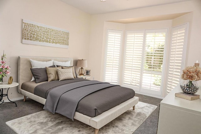 bedroom featuring multiple windows and dark carpet