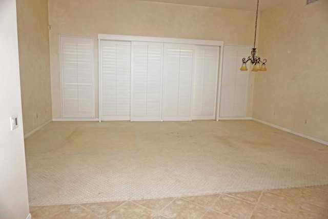 unfurnished bedroom with tile patterned flooring, a notable chandelier, and a closet