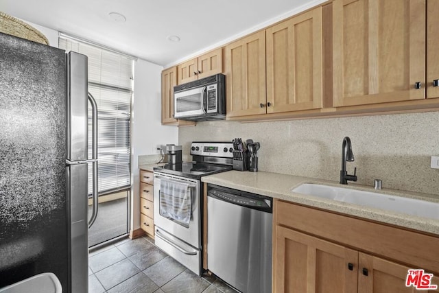 kitchen featuring appliances with stainless steel finishes, dark tile patterned floors, sink, and light brown cabinets