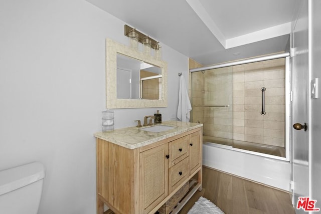 full bathroom featuring hardwood / wood-style flooring, vanity, enclosed tub / shower combo, and toilet