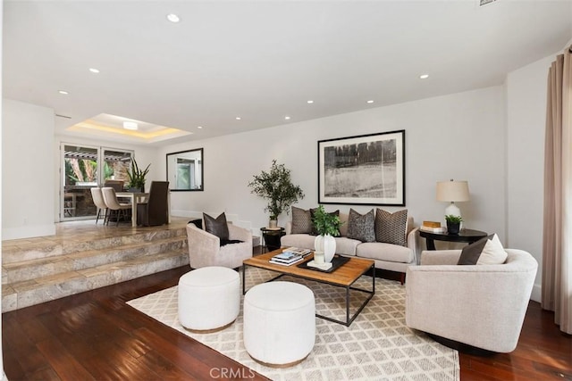 living area with baseboards, a tray ceiling, hardwood / wood-style flooring, and recessed lighting