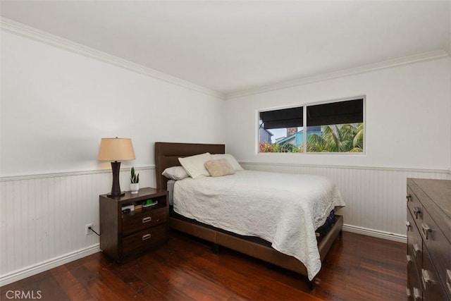 bedroom with crown molding, a wainscoted wall, and dark wood finished floors