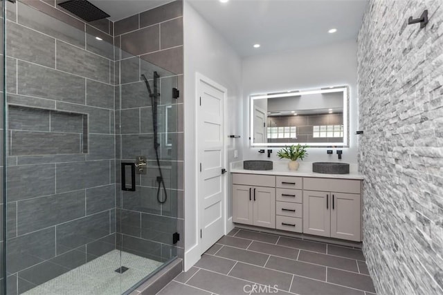 bathroom featuring double vanity, tile patterned flooring, a shower stall, and a sink