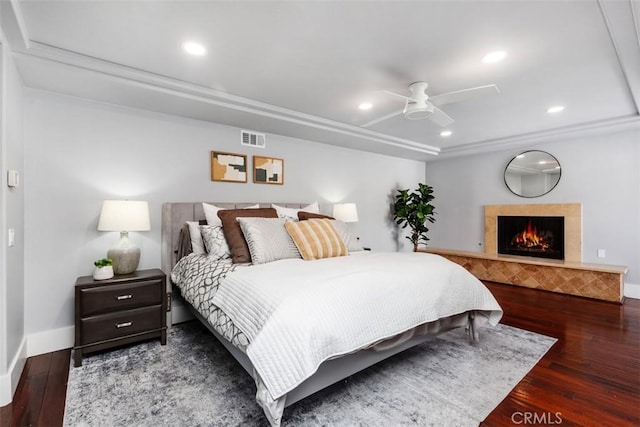 bedroom with a warm lit fireplace, recessed lighting, visible vents, baseboards, and wood-type flooring