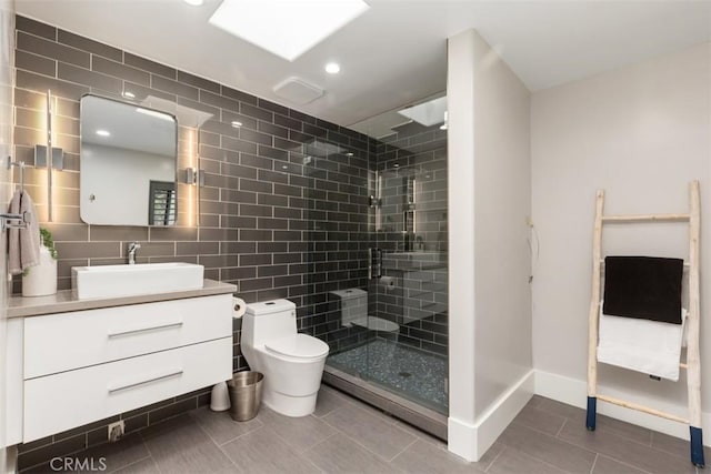 full bathroom with toilet, vanity, baseboards, tile walls, and a stall shower