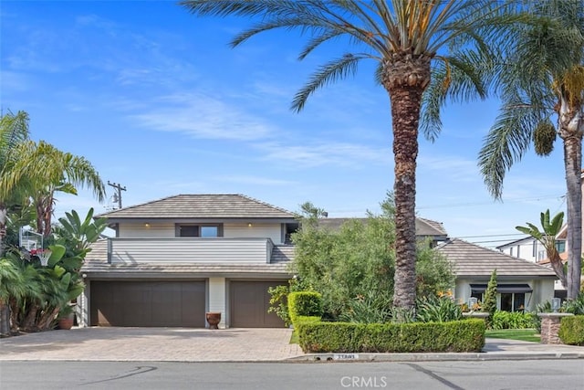 view of front of property with decorative driveway, a balcony, and an attached garage