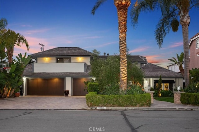 view of front facade featuring a garage, decorative driveway, and a balcony