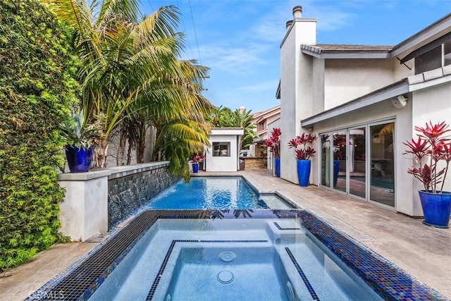 outdoor pool with a patio area and an in ground hot tub