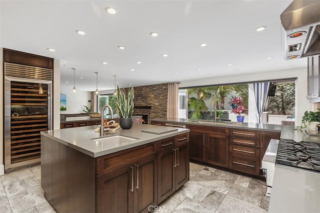 kitchen featuring a healthy amount of sunlight, a kitchen island with sink, wine cooler, and a sink