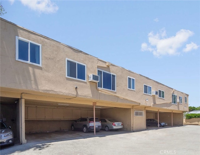 rear view of property with a wall unit AC and a carport