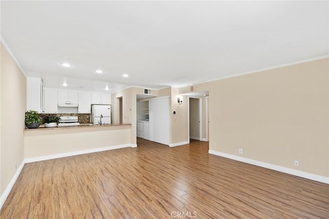 unfurnished living room with light hardwood / wood-style flooring, sink, crown molding, and washing machine and dryer