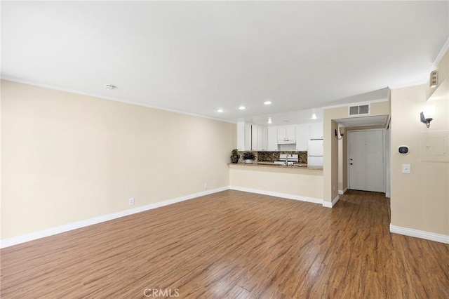 unfurnished living room with sink, crown molding, and light hardwood / wood-style flooring