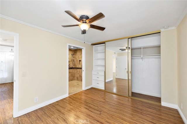 unfurnished bedroom featuring hardwood / wood-style flooring, ornamental molding, and ensuite bath