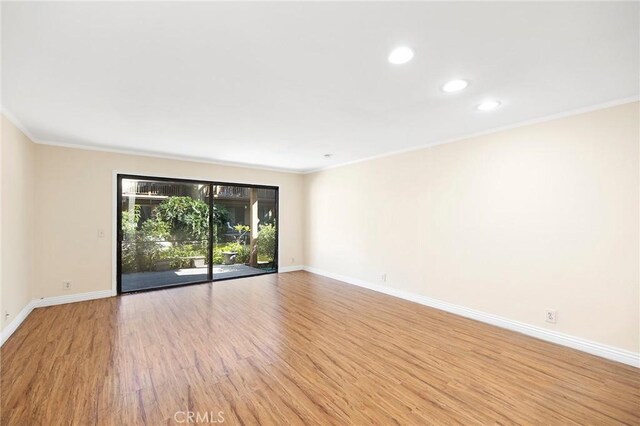 empty room with light hardwood / wood-style floors and crown molding