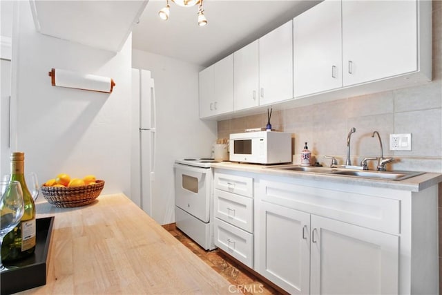 kitchen with backsplash, sink, white appliances, and white cabinetry