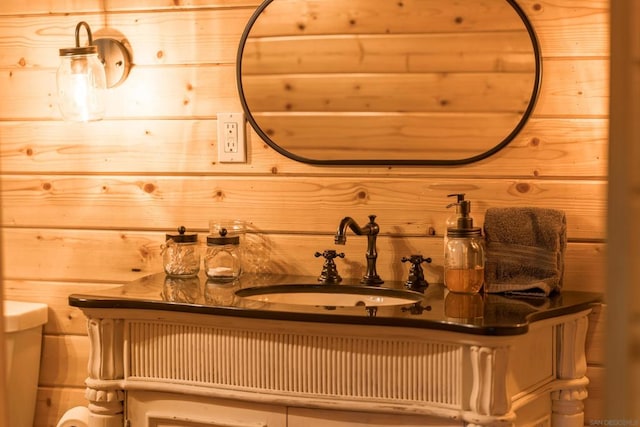 bathroom with sink, wood walls, and toilet