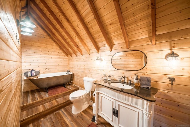 bathroom featuring vanity, wood-type flooring, a tub to relax in, lofted ceiling with beams, and toilet