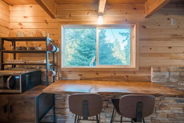 dining area featuring wood walls and beam ceiling