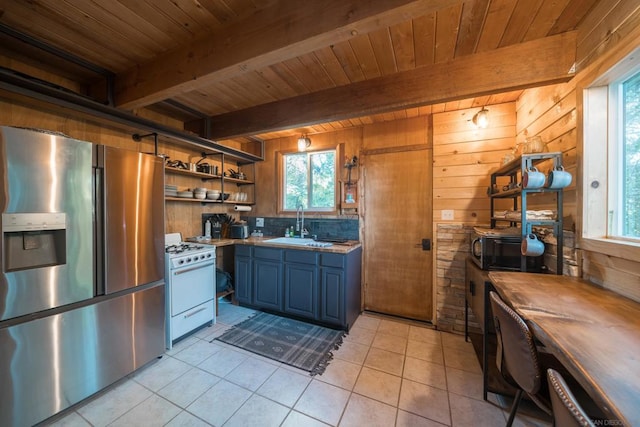 kitchen featuring blue cabinets, wood walls, light tile patterned floors, stainless steel fridge with ice dispenser, and white range with gas stovetop