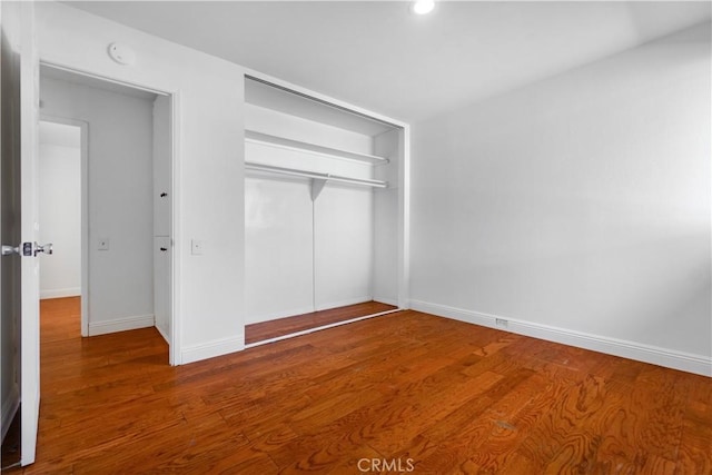 unfurnished bedroom with wood-type flooring and a closet