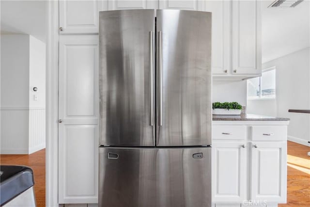 kitchen with white cabinets, stainless steel fridge, and light hardwood / wood-style flooring