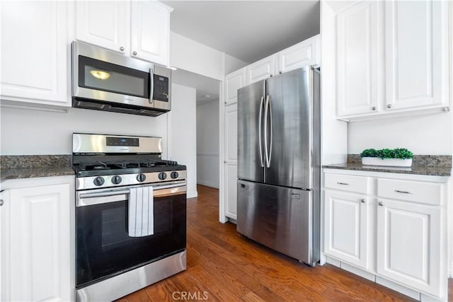 kitchen featuring white cabinets, dark hardwood / wood-style flooring, appliances with stainless steel finishes, and dark stone counters