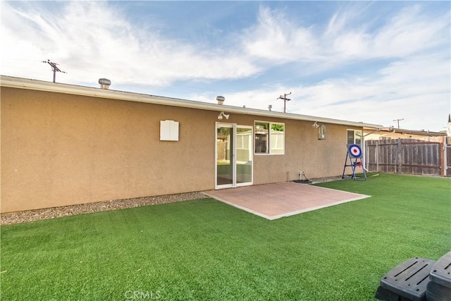 back of property with a patio area, a yard, fence, and stucco siding