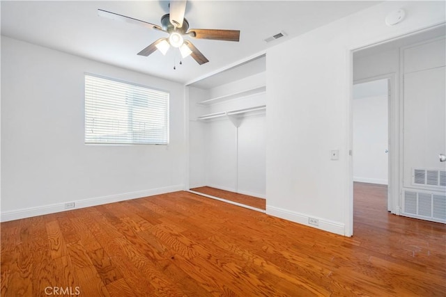 empty room with ceiling fan, visible vents, baseboards, and wood finished floors