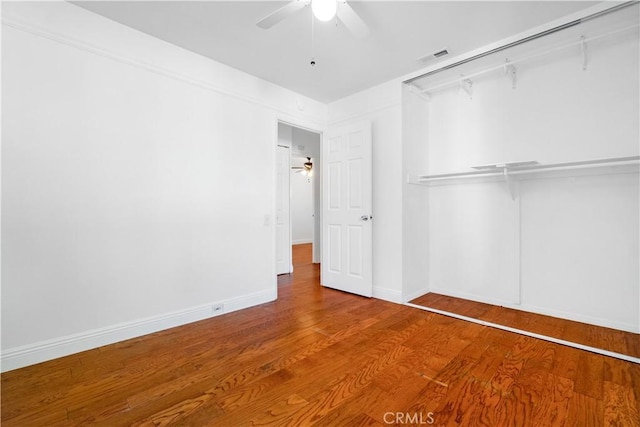 unfurnished bedroom featuring ceiling fan, wood-type flooring, and a closet