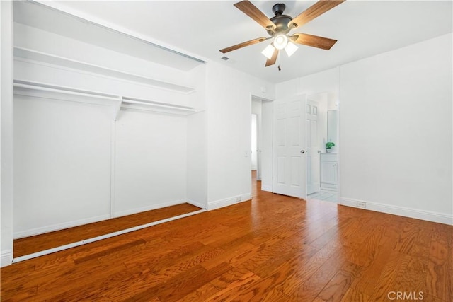 unfurnished bedroom with ceiling fan, wood-type flooring, and a closet