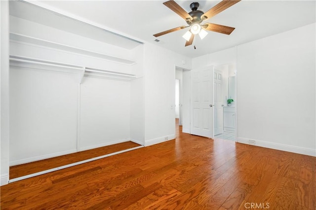 unfurnished bedroom featuring a ceiling fan, visible vents, wood finished floors, baseboards, and a closet