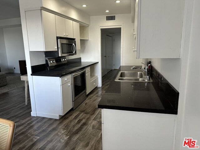 kitchen featuring sink, white cabinets, dark wood-type flooring, and appliances with stainless steel finishes