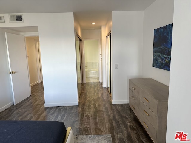 unfurnished bedroom featuring ensuite bathroom and dark hardwood / wood-style floors