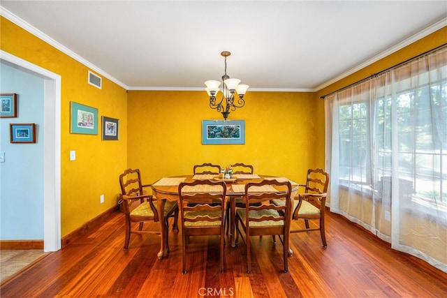 dining area with an inviting chandelier, crown molding, and dark wood-type flooring