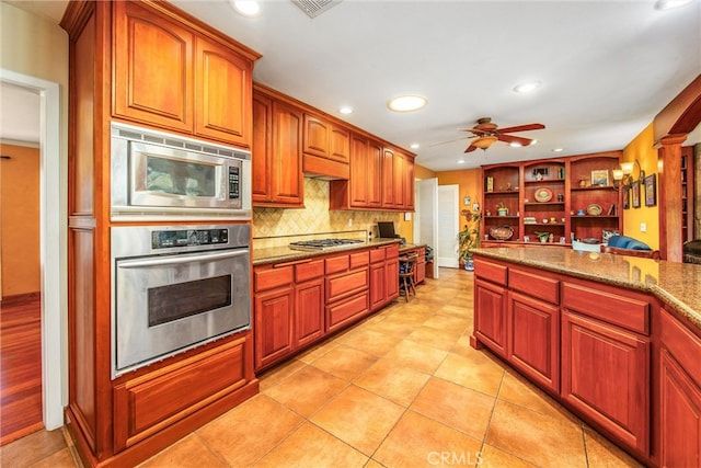 kitchen featuring ceiling fan, appliances with stainless steel finishes, backsplash, light tile patterned floors, and light stone counters