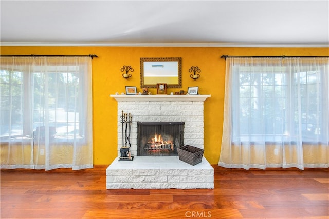 living room with ornamental molding, a brick fireplace, and wood-type flooring