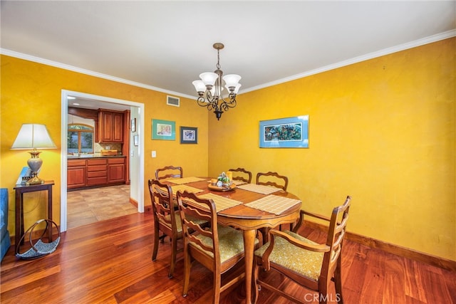 dining space featuring hardwood / wood-style flooring, ornamental molding, and an inviting chandelier