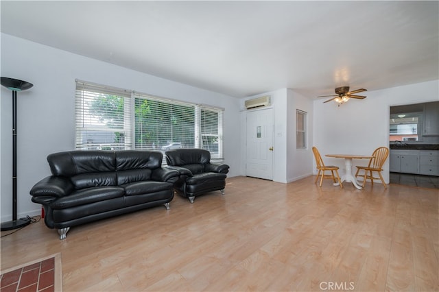 living room featuring a wall mounted AC, ceiling fan, and light hardwood / wood-style floors