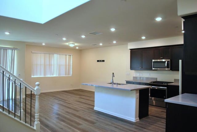 kitchen with a center island with sink, sink, stainless steel appliances, and dark wood-type flooring