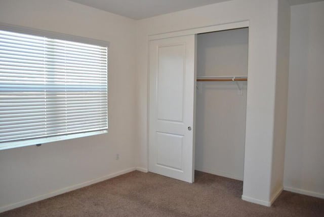 unfurnished bedroom featuring light carpet and a closet