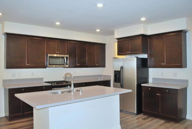 kitchen with sink, an island with sink, light hardwood / wood-style flooring, and appliances with stainless steel finishes