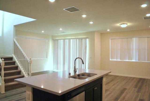 kitchen with stainless steel dishwasher, dark hardwood / wood-style flooring, sink, and a kitchen island with sink